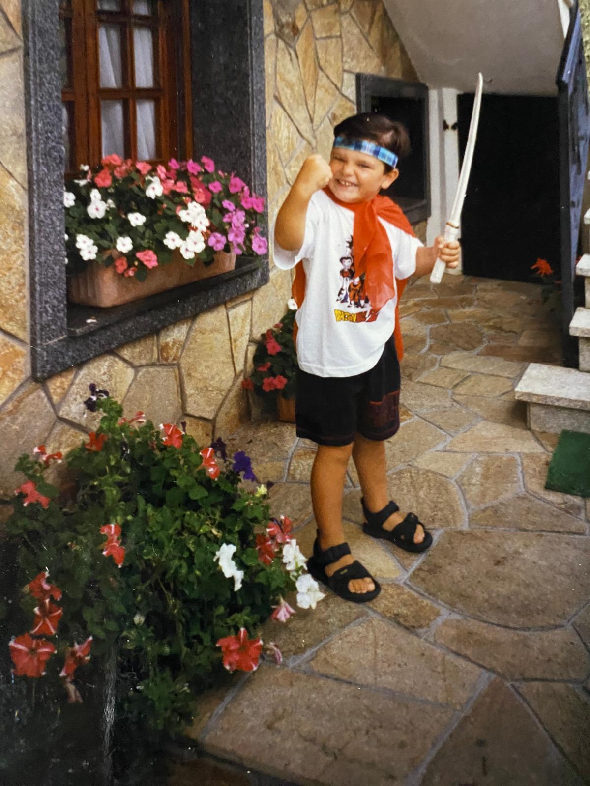 De pequeño, sonriendo junto a las flores